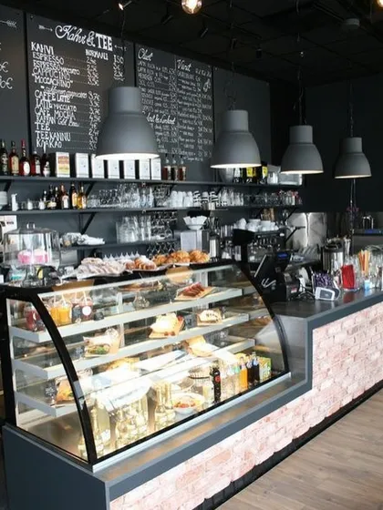 A well-designed service counter is crucial for any cafe. Here, we designed a functional counter area with a brick facade, a curved glass display for pastries, and a dark, moody color scheme that contrasts with the warm lighting, ensuring an efficient workflow and an attractive point of sale.