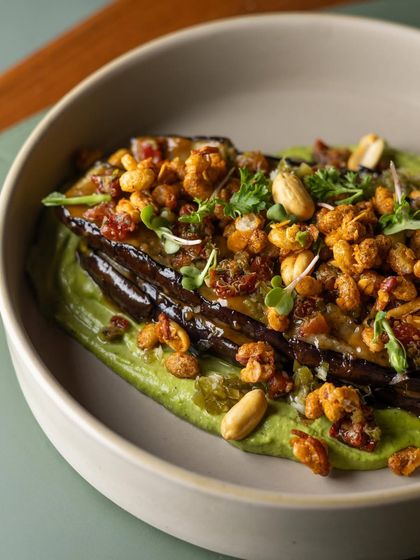 A close-up of the Miso Grilled Aubergine, highlighting the glossy glaze on the perfectly grilled vegetable and the crunchy granola topping.