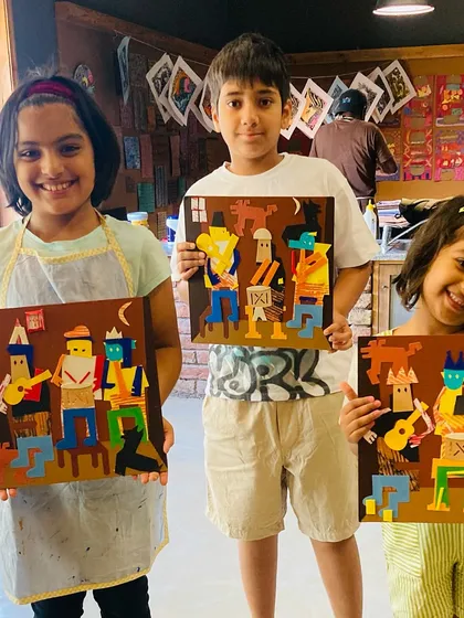 Three happy students display their Picasso-inspired "Three Musicians" collages.