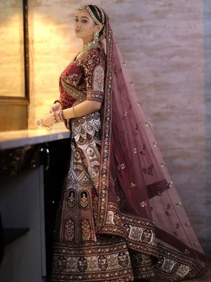 A side profile showcasing the elegant hair bun and the way the dupatta is draped over the head, framing the stunning bridal jewellery.