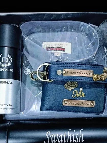A stylish blue and black gift hamper featuring a personalized wallet, keychain, and temperature bottle, along with a shirt and deodorant.