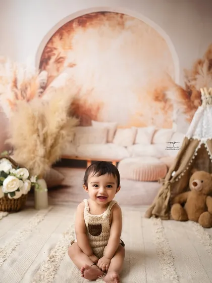 A happy baby boy enjoying his sitter session in a warm, boho-inspired setting. His bright smile lights up the entire frame.