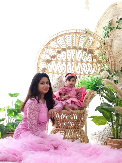 A beautiful portrait of a mother and daughter in a bright, bohemian-style setup. The large peacock chair and lush greenery create a stunning backdrop for family photos.