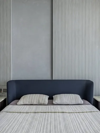 The minimalist master bedroom in 'The Grey House' uses a calming grey palette and clean lines to create a serene sleeping space.