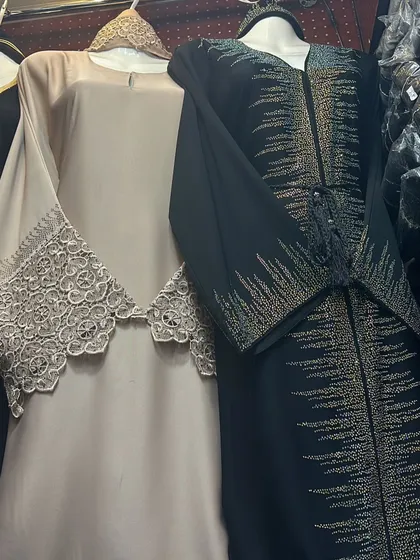 A look at two very different styles. One is a beige abaya with a beautiful lace overlay, and the other is a black piece with sparkling silver and gold beadwork.