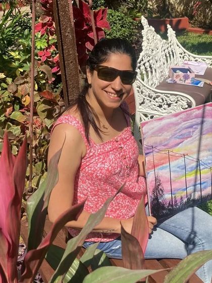 A happy student relaxing with her beautiful sailboat painting, created during one of our serene outdoor art sessions.