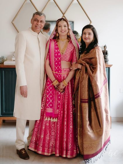 A beautiful family portrait. The bride's soft makeup ensures she looks radiant and fresh, standing proudly with her parents.