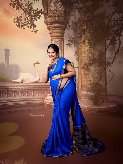 A confident and joyful pose in a traditional blue saree. This portrait captures the beauty and strength of motherhood, framed by a classical, artistic setting.