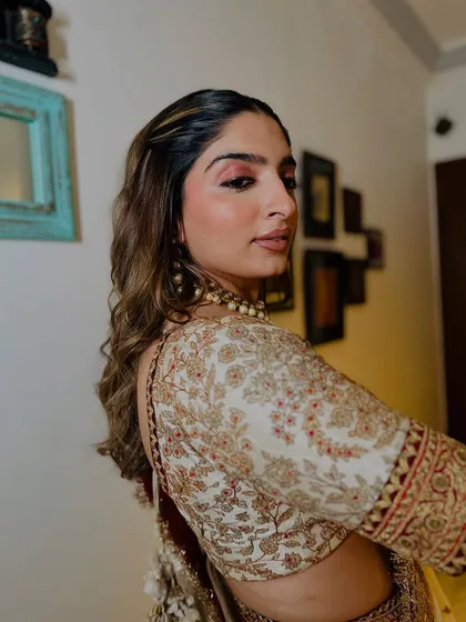 A graceful side profile that highlights the soft waves in her hair and the delicate shimmer of her eye makeup. The entire look is one of effortless elegance.