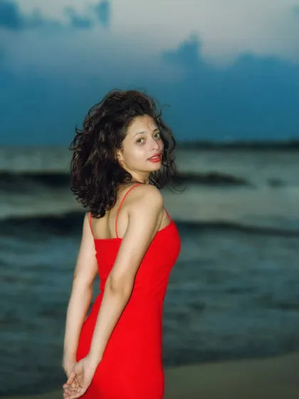 A classic over-the-shoulder look. The flash freezes the motion of her hair and the waves, creating a crisp, clear image against the dark sea.
