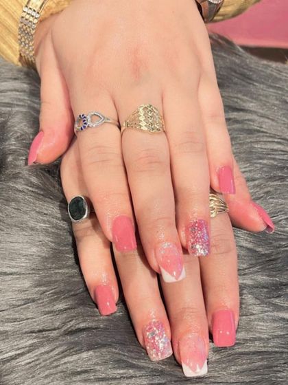 A fun and playful set combining solid pink nails with accent nails featuring a glitter ombré and a white V-tip.