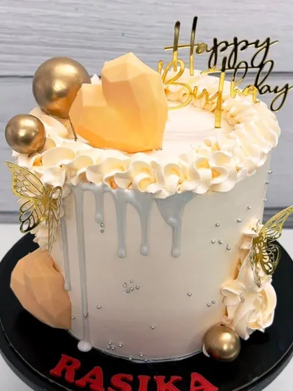 A closer look at the beautiful details on this orange, white, and gold birthday cake.