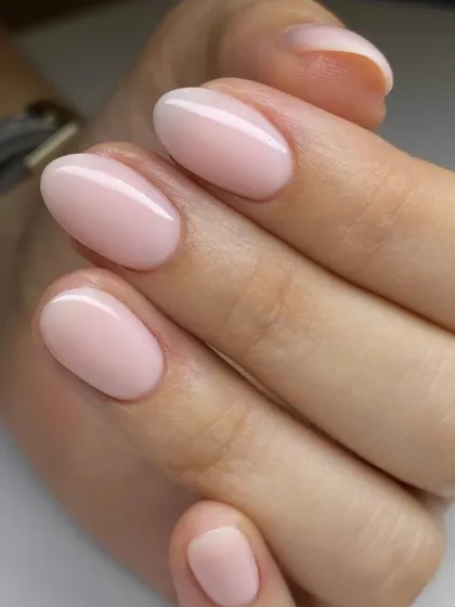 A soft, milky pink manicure on oval-shaped nails. This delicate and clean look is timelessly elegant and perfect for any occasion.
