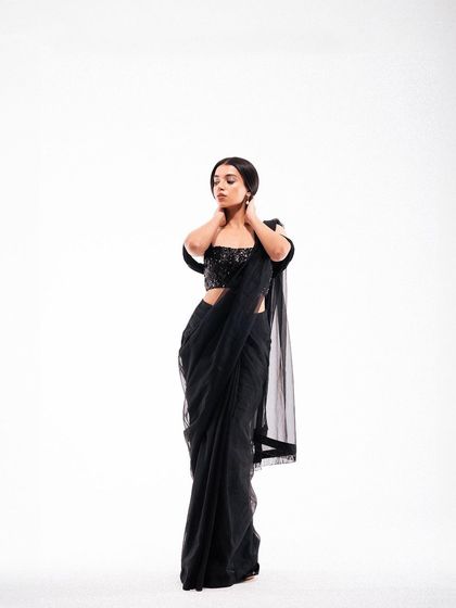 A full-length shot that captures the complete silhouette of the modern black saree. The simple, elegant pose against a white background is perfect for a lookbook or e-commerce.