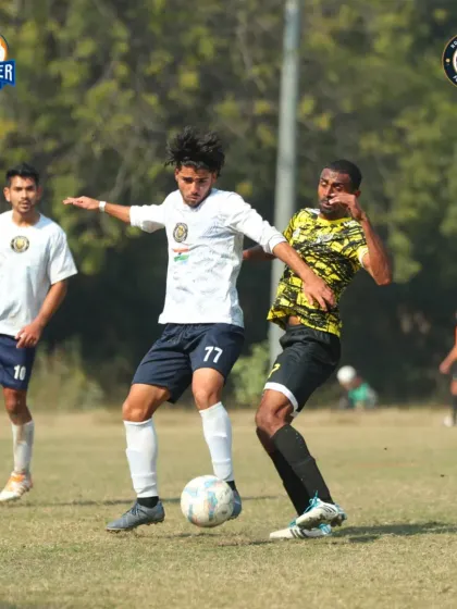 A player shields the ball from an opponent, using their body to protect possession.