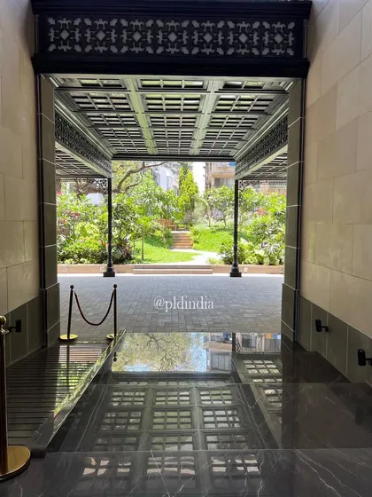 The entrance to the garden is framed by an elegant black pavilion, creating a formal gateway to the more naturalistic landscape beyond. The dark marble floor reflects the garden, blurring the boundary.