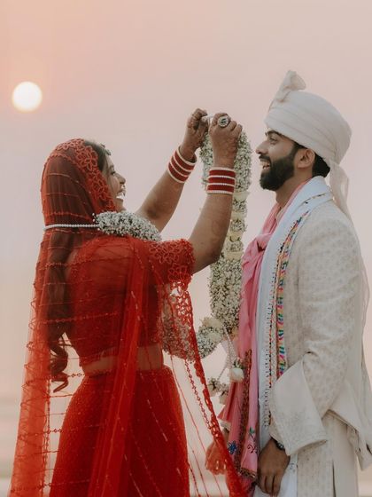 The Varmala exchange against the setting sun. This is a pivotal moment, and I capture it with a cinematic feel, highlighting the beauty of the ritual and the location.