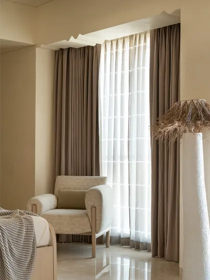 The master suite in the 'Soft Serve' project is enveloped in a timeless taupe. The custom bed and vanity feature abstract patterns in Movingue White veneer, with scalloped motifs framing the bay window.
