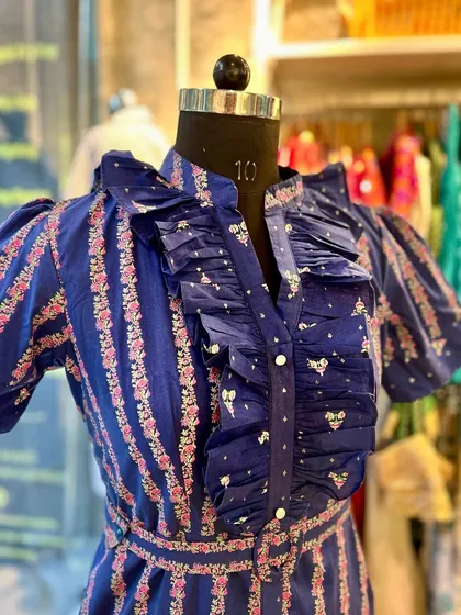 A close-up view of the intricate ruffle neckline on the retro-style dress. The three layers of ruffles add texture and a touch of vintage glamour to the floral and striped fabric.