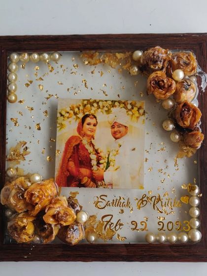 This is a square wooden frame filled with resin to preserve a couple's wedding flowers. I added their photo, names, and wedding date, with pearl details for an elegant touch.