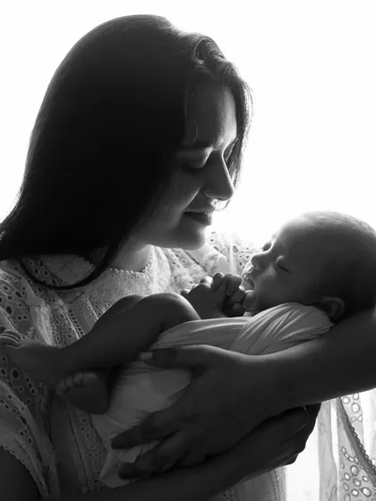 A close-up of a mother gazing at her newborn baby. The black and white edit adds a timeless, classic feel to this intimate moment.