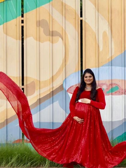 A full-length view of the red sequin maternity gown with its impressive flowing trail. This dress is perfect for making a bold statement during your pregnancy photoshoot.
