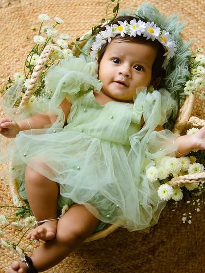 An overhead shot of the baby in the basket, showing the full setup with the jute rug and flowers.