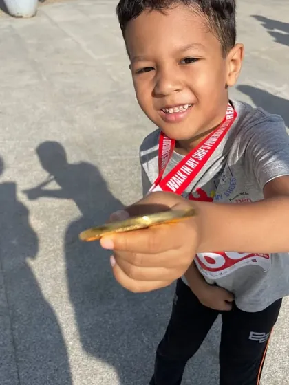A young participant proudly shows off his medal from the 'Walk in My Shoes' run. Every step taken was a step towards a more inclusive and caring community.