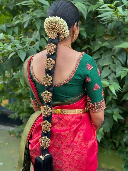 A detailed view of a traditional South Indian bridal hairstyle. This intricate poola jada features a long, neat braid adorned with fresh jasmine flowers and classic gold jadai billai, creating a timeless and elegant look for the wedding ceremony.