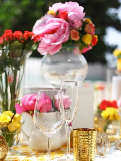 A close-up of a vibrant floral centerpiece with elegant glassware. We believe in creating a complete sensory experience, where beautiful decor complements our exquisite food.