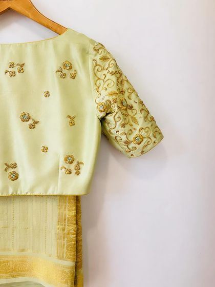A close-up of the pistachio green blouse, showing the intricate gold zardosi embroidery on the sleeve and scattered motifs.
