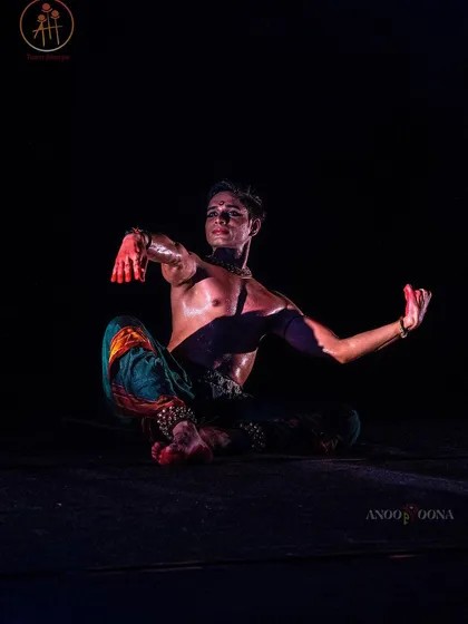 A powerful seated pose from 'Nagamandala' at the Aharya National Dance Festival. The red paint on the hands is a significant part of the character's costume.
