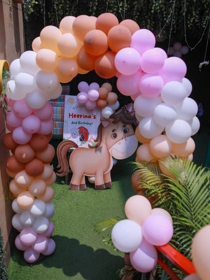 A charming entrance to a barnyard-themed party, featuring a balloon arch in rustic colors and a cute horse cutout to welcome the little farmers.