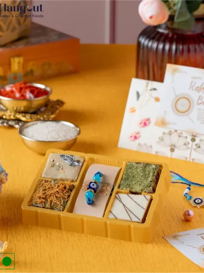 This limited-edition brownie box is perfect for Rakshabandhan. It features unique fusion flavors like Matcha, Kaju Katli, and Kunafa brownies, and comes paired with an Evil Eye Rakhi.