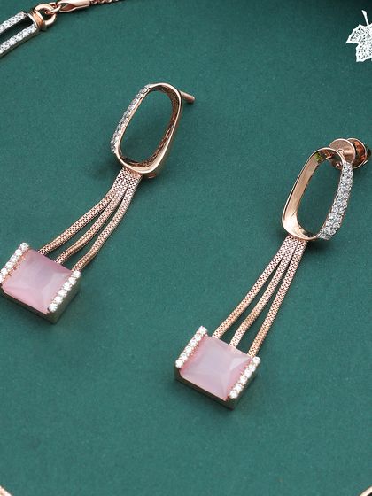 The earrings from our Blush Pink set. The design features a cascade of rose gold chains culminating in a soft pink gemstone, framed by a delicate diamond halo for a touch of sparkle.