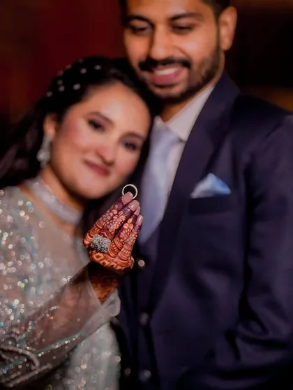 The promise of forever, perfectly framed. The bride proudly displays her engagement ring, with her and her partner sharing a happy, gentle moment in the background.