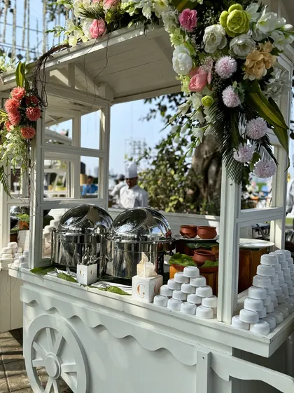 A charming white cart beautifully adorned with flowers, serving as a food station. This is an example of how we can create unique and picturesque service points for your event.