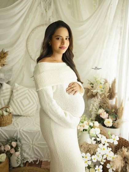 A classic and beautiful solo portrait of a mother-to-be in a cozy white sweater dress. She looks radiant and serene in our all-white boho setup.