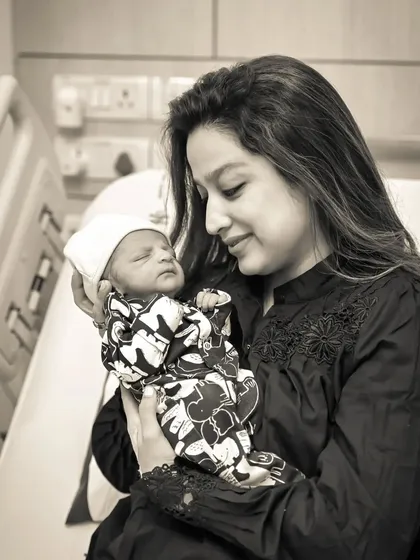 A tender black and white photo of a new mother holding her newborn baby for the first time in the hospital.