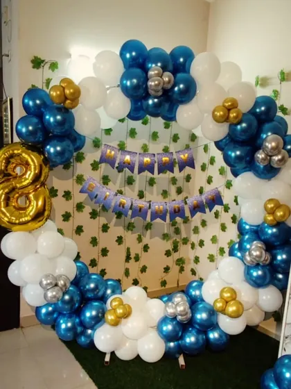An 8th birthday decoration with a blue, white, and gold balloon ring. The setup includes a large foil number '8' and a 'Happy Birthday' banner.
