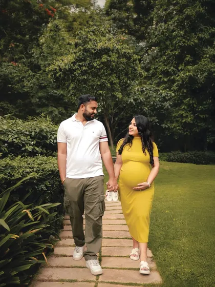 Walking towards their next chapter together. This candid shot in a park, with the couple holding tiny baby shoes, is a sweet and symbolic way to document their journey to parenthood.