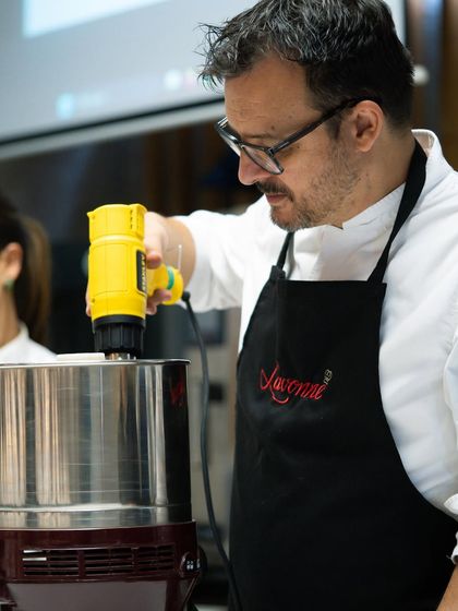 A chef uses an industrial blender to refine the chocolate, demonstrating the machinery and techniques used in professional chocolate production.