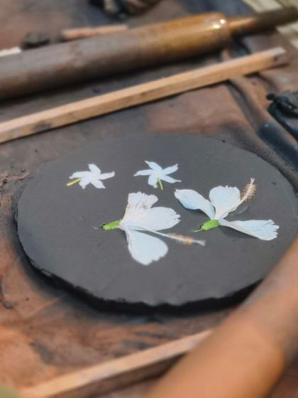 A student uses real flowers to create impressions in a slab of clay. This is a beautiful and simple technique to transfer natural textures and patterns onto pottery.