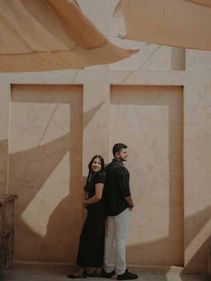 A playful back-to-back pose against a textured wall, using the beautiful afternoon light and shadows of the location.