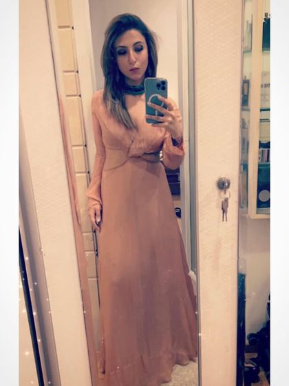 A mirror selfie in a long, blush-colored dress. The elegant drape and twist-front detail make it a beautiful piece for an event.