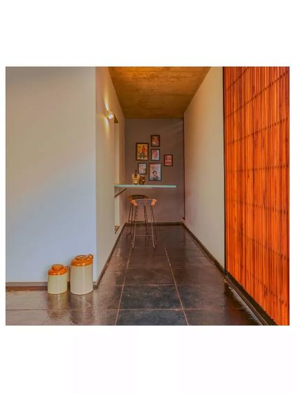 A cozy nook in the Aayi House, featuring a simple bar-height table and stools. The use of natural materials like wood and stone tiles adds to the home's warm, earthy feel.
