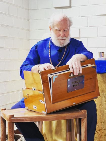 Nayaswami Haridas immersed in playing the harmonium. The instrument is a constant companion in our kirtans, its resonant tones supporting the voices and deepening the devotional experience for everyone.