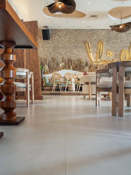 Another view of the seamless flooring at One 8 Commune. The light-colored, large-format tiles make the space feel open and airy, balancing the darker wood tones and textured walls.