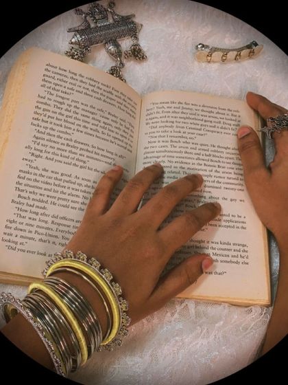 A closer look at the yellow-themed set, showing the oxidised necklace, Kundan hairclip, and silk thread bangles against a book, creating an aesthetic vibe.
