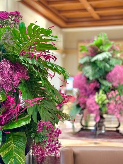 A focused shot showing the two complementary pink and green arrangements in the lobby. Creating a cohesive visual language across the space ensures a harmonious and impactful design.